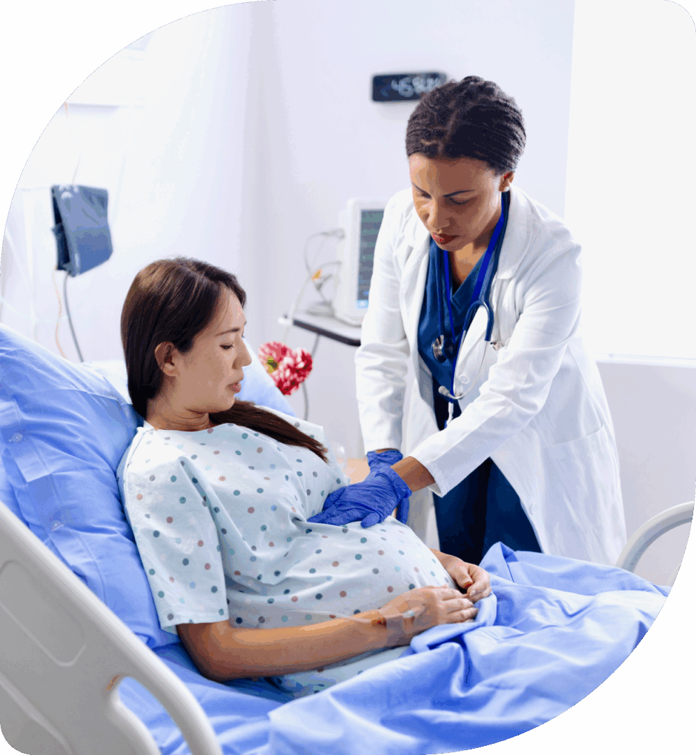 Doctor examining pregnant woman in hospital bed.