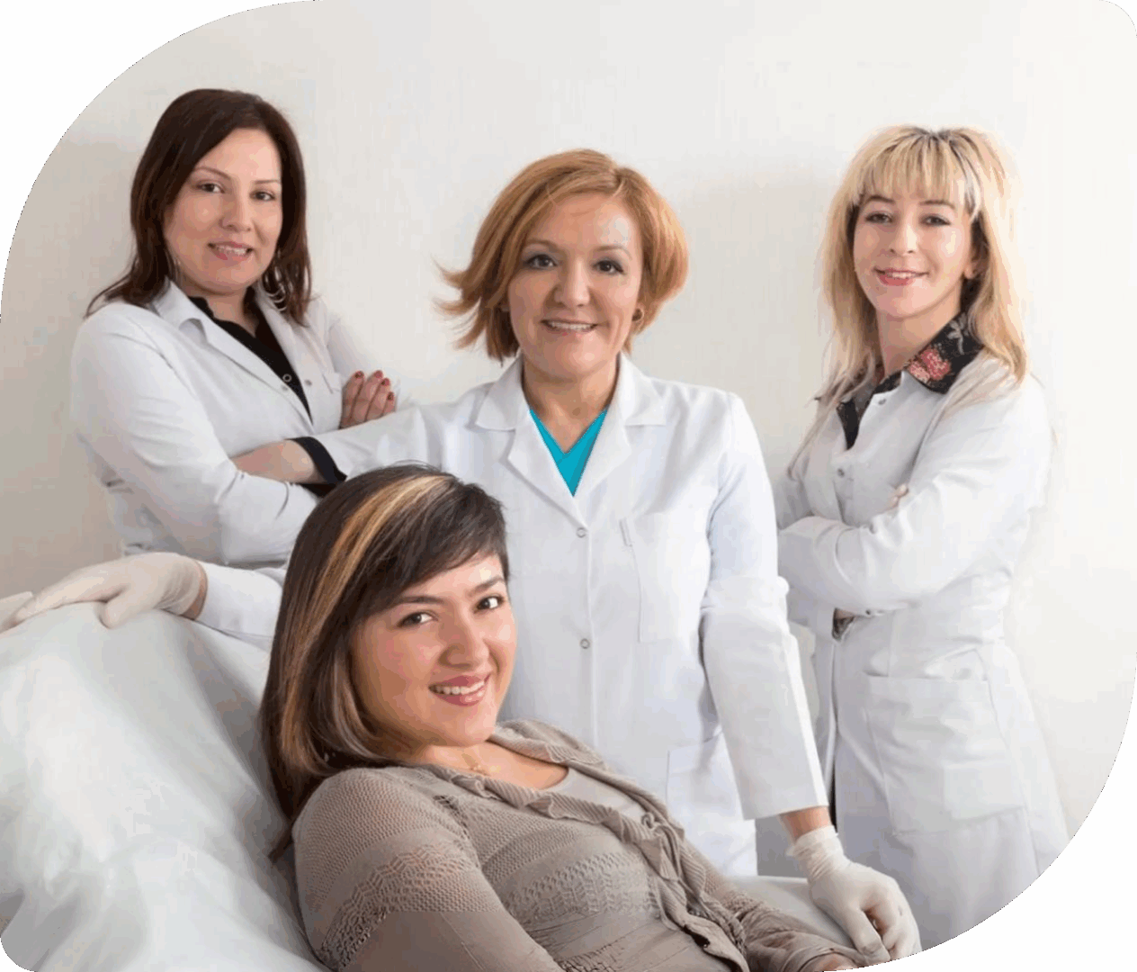 Women in lab coats with patient smiling.