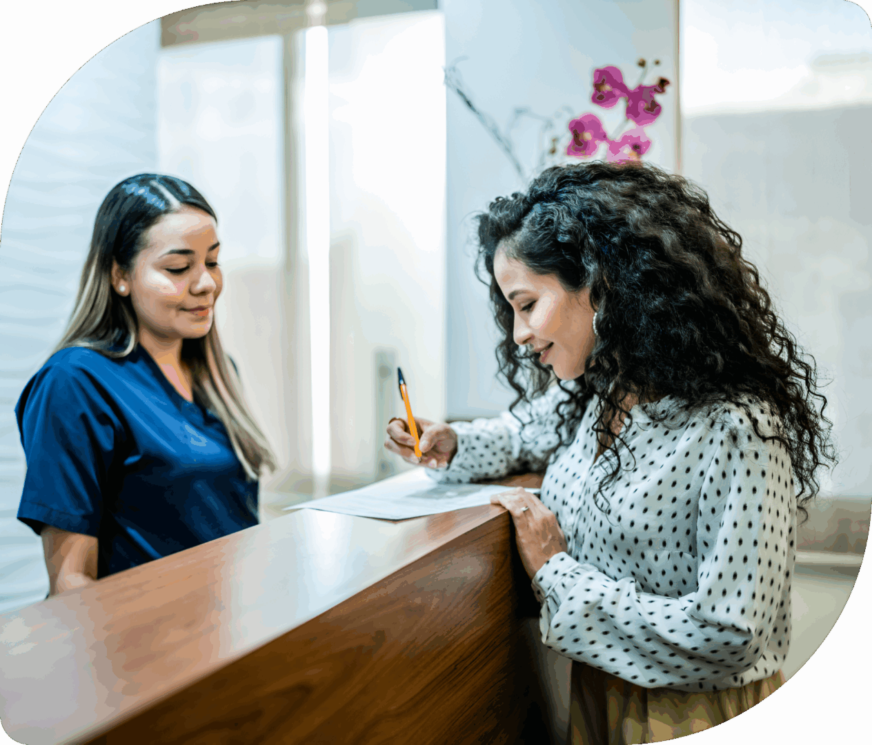 Woman signing papers at reception desk.